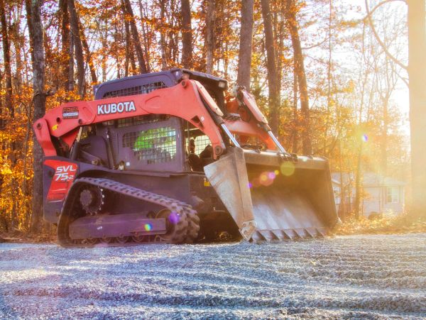Kubota construction vehicle on gravel with autumn trees.