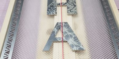 A floral-patterned letter A on a mesh surface.