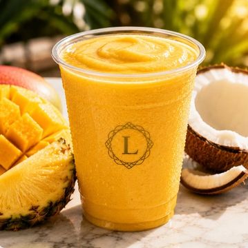 Tropical fruit smoothie in a plastic cup with pineapple, mango, and coconut.