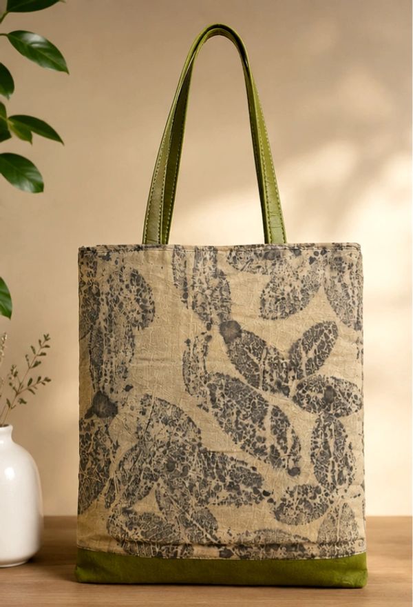 Eco-friendly tote bag with leaf print and green handles.