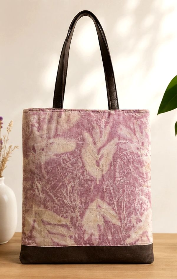Pink and beige tote bag with dark brown handles on a wooden surface.