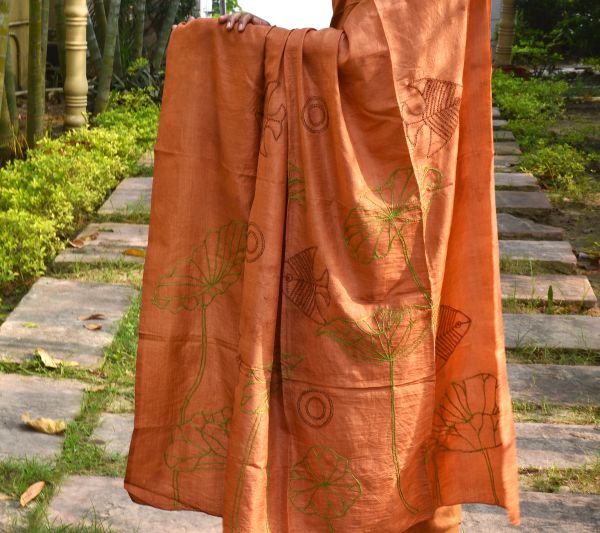 Orange fabric with green and brown leaf and fish designs.