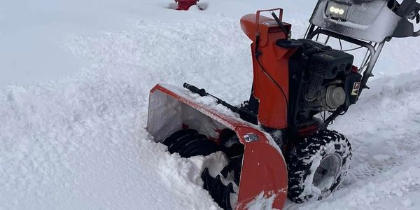 Red snowblower clearing snow.