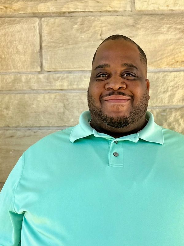 Smiling man in a turquoise polo shirt.