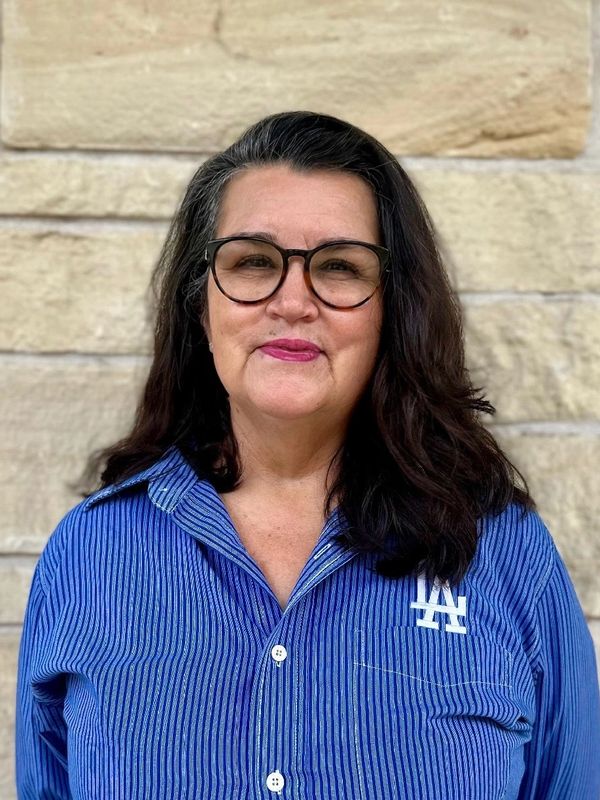 Smiling woman with glasses wearing a blue LA Dodgers shirt.