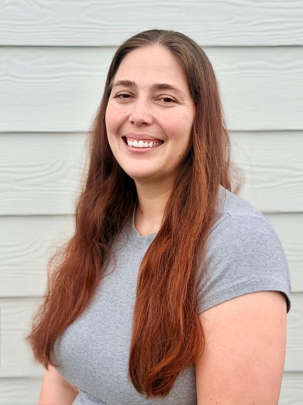 Smiling woman with long brown hair and grey shirt.