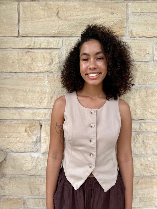 Young woman smiling against a stone wall.