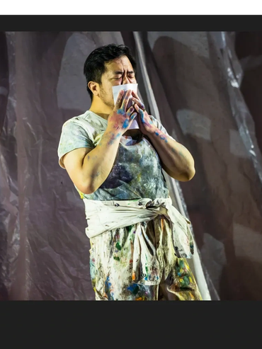 Painter wiping his face with a cloth, covered in paint.
