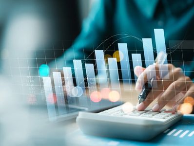 Person using calculator with financial graph overlay.