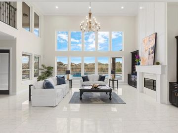 Bright, spacious living room with large windows and elegant chandelier.