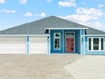 Modern blue house with red front door and two-car garage under a blue sky.