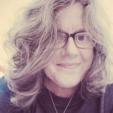 Smiling woman with glasses and wavy gray hair.