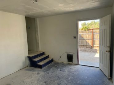 Empty room with steps and an open door leading outside.