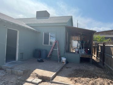 Backyard of a house under renovation with construction materials and tools.
