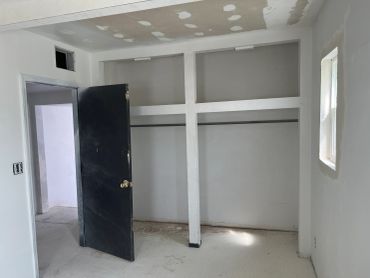 Unfinished room with a black door and built-in closet frame.