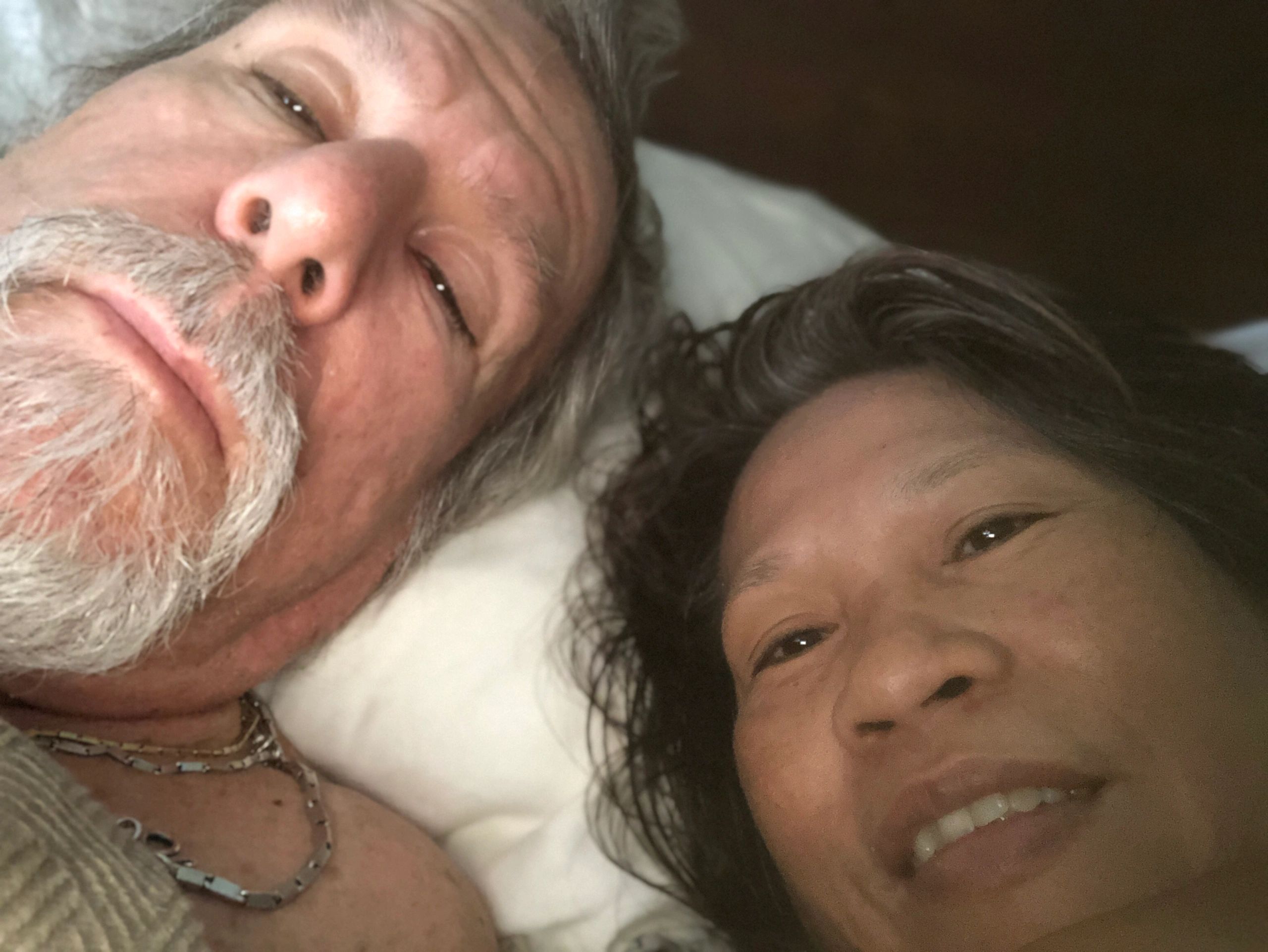 Close-up selfie of a smiling couple lying down together.