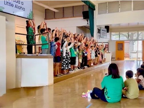 Children performing on stage with audience watching.