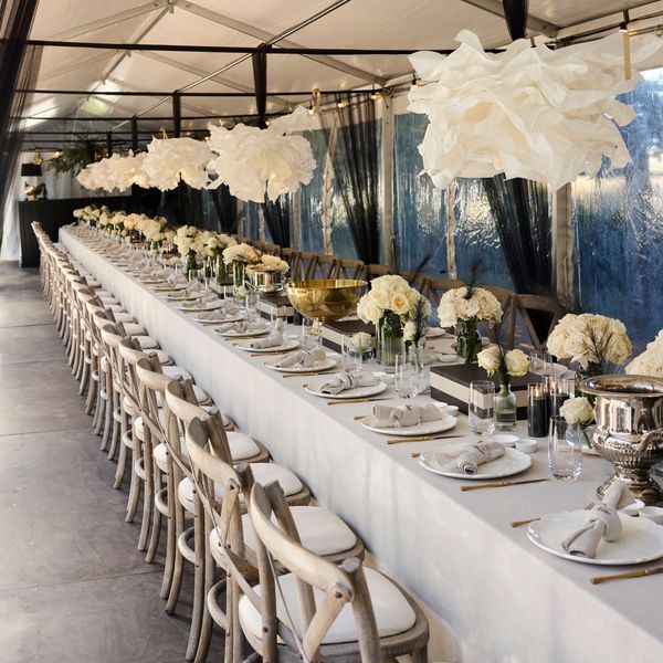 Elegant long dining table set with white flowers and unique pendant lights.