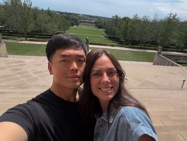 A couple taking a selfie outdoors on a sunny day.