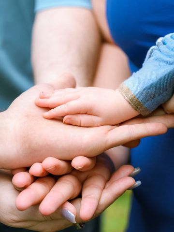 A baby's hand resting gently on an adult's hand symbolizing care and protection.