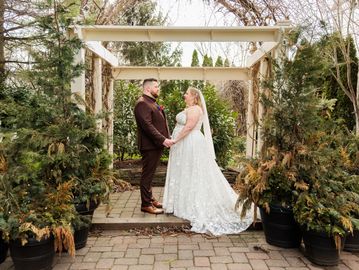 Bride and groom holding hands under a garden arch during outdoor wedding.