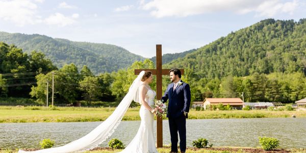 Bride and groom with cross in scenic outdoor setting.