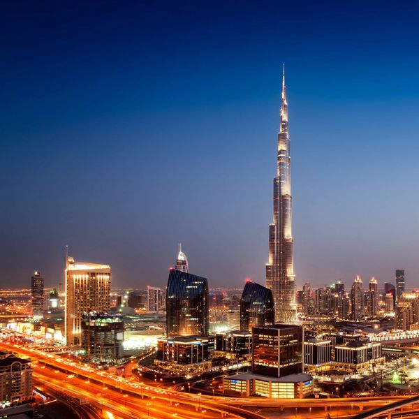 Night skyline of Dubai with the illuminated Burj Khalifa and vibrant city lights.
