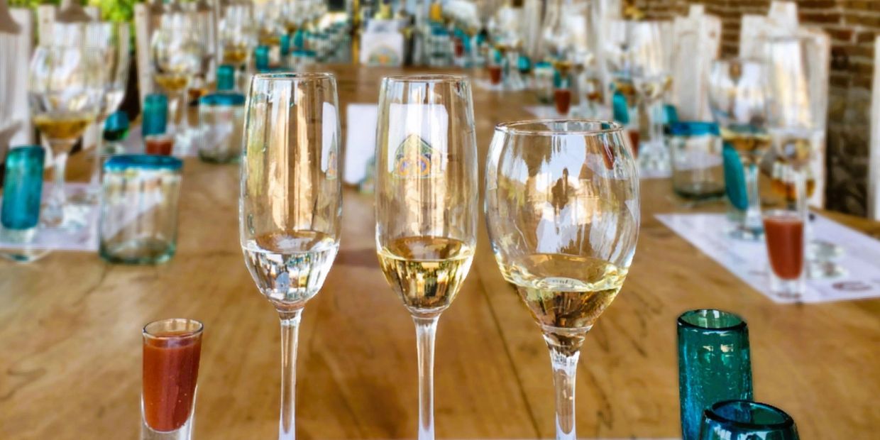 Three glasses with drinks on a wooden table at a festive gathering.