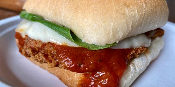 Close-up of a crispy chicken sandwich with marinara sauce and spinach.