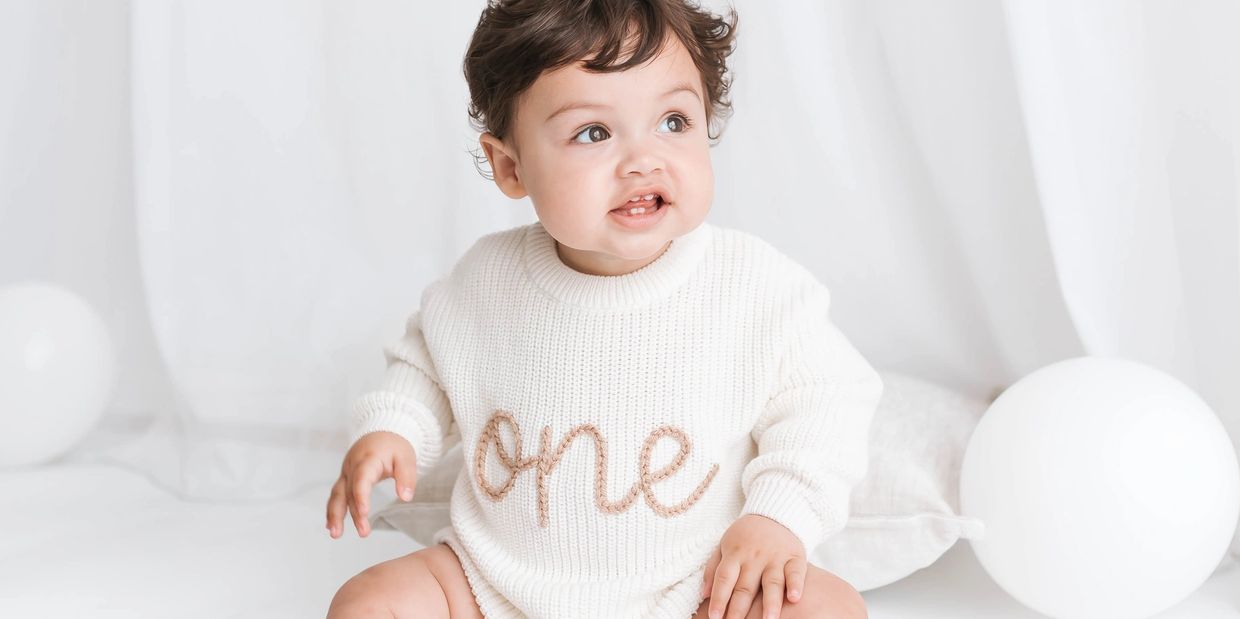 Baby wearing cream “one” jumper during first birthday photoshoot in Milton Keynes.