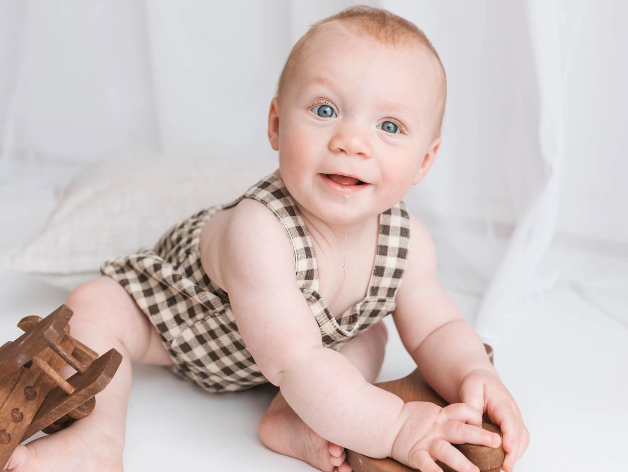 Smiling baby playing during sitter photoshoot in Milton Keynes.