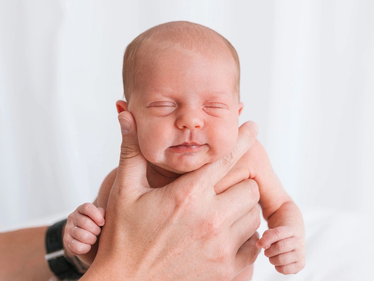 Newborn photoshoot in Milton Keynes, 12-day-old baby supported by parent’s hand