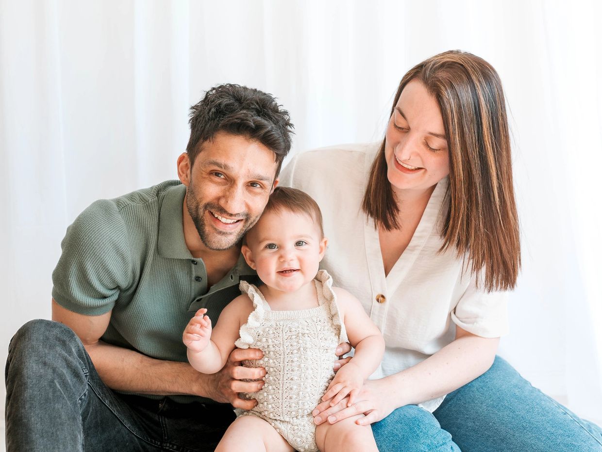 Family photoshoot in Milton Keynes, parents sitting with baby and smiling together.