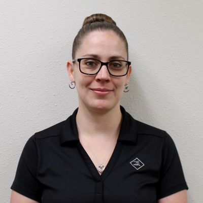 Woman with glasses and a black collared shirt smiles.