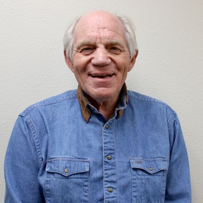 Smiling elderly man in a denim shirt.