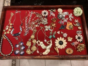 A collection of various vintage jewelry pieces in a red display tray.