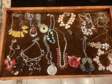 Assorted necklaces and bracelets on a brown tray.