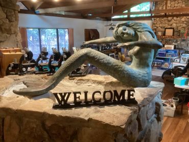 Mermaid sculpture on a stone pedestal with a welcome sign.