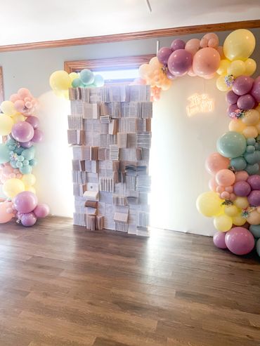 Balloon arch and book pages door decor.