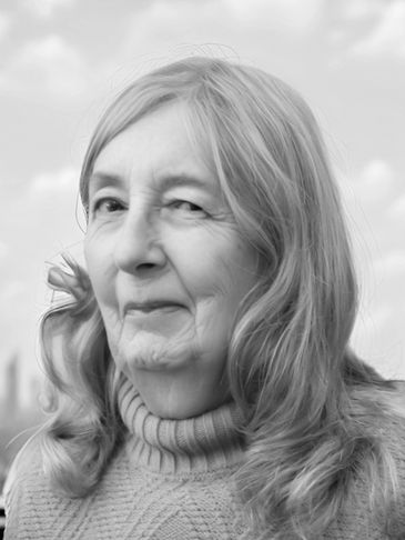 Close-up of an elderly woman with a gentle smile, wearing a knitted sweater.