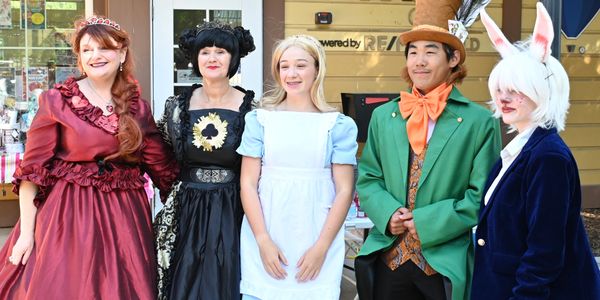 Five people dressed as characters from Alice in Wonderland posing outdoors.