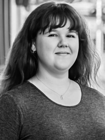 Black and white portrait of a smiling young woman with long hair and bangs.