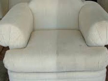 A beige cushioned armchair with rounded armrests.