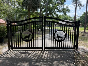 Black metal gate with wildlife cutouts in a residential area.