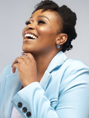 Joyful woman in light blue blazer laughing brightly.