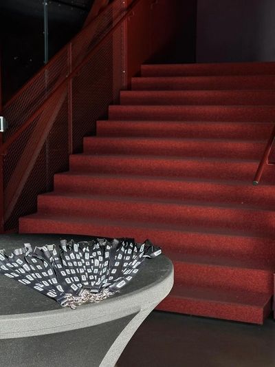 A red-carpeted staircase beside a table with black and white patterned fans.