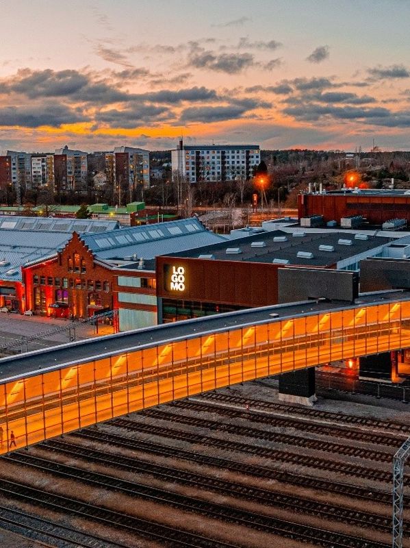 Sunset view of Logomo center with illuminated bridge over railway tracks.