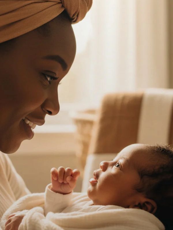 A mother lovingly gazes at her baby wrapped in a cozy blanket.