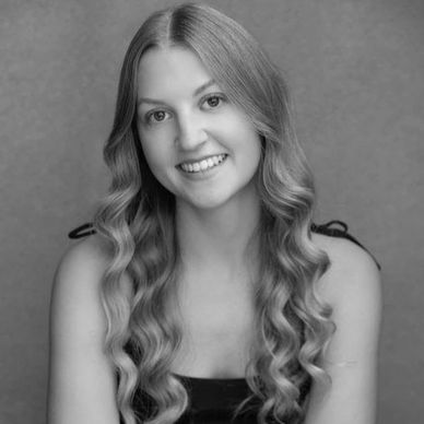 Black and white portrait of a smiling young woman with long wavy hair.