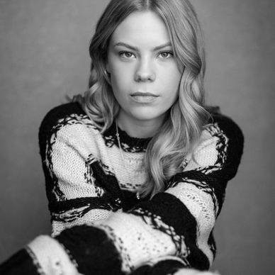Black and white portrait of a woman with wavy hair and a striped sweater.